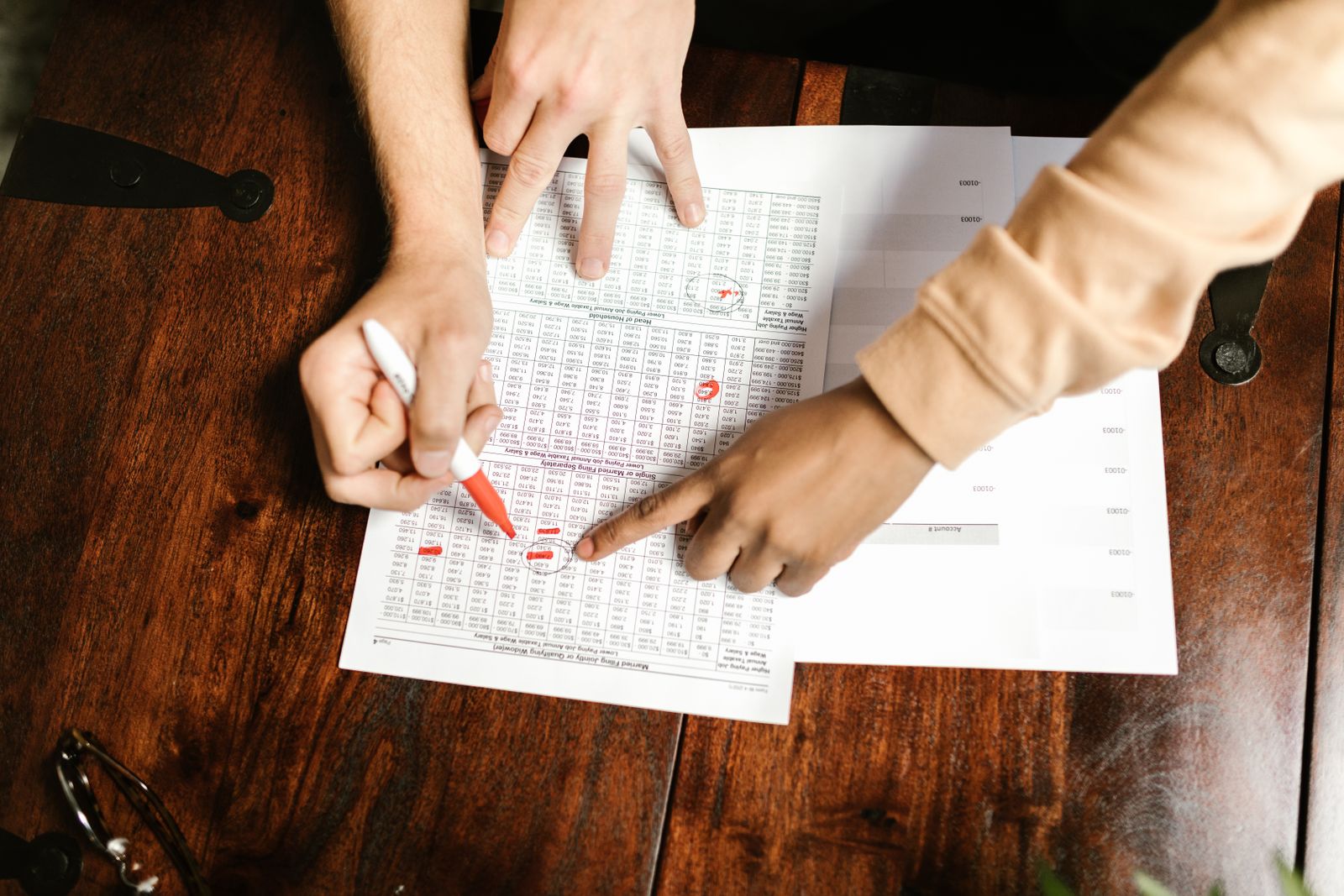 Hands reviewing a document with a red pen